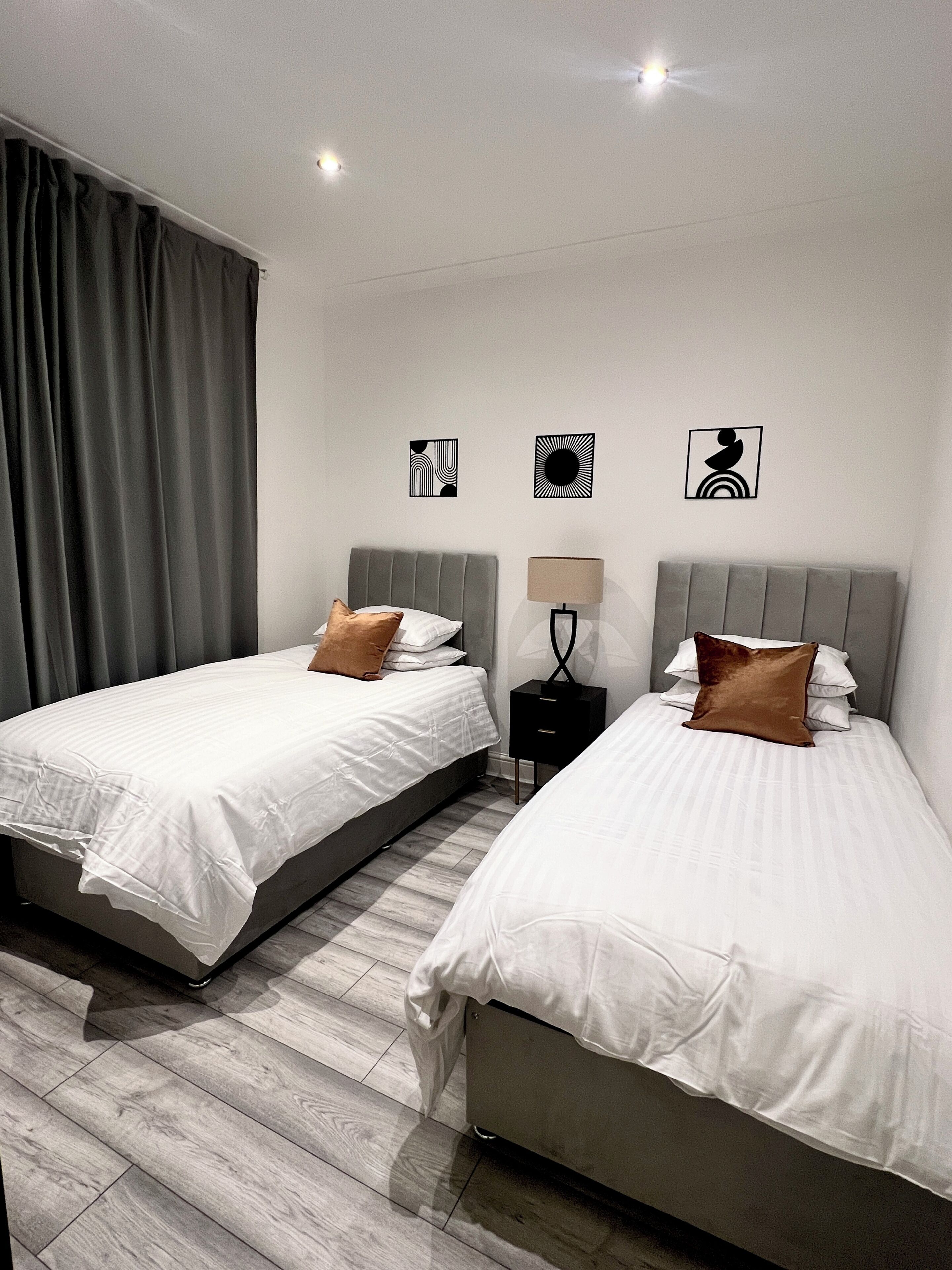 Une chambre d’h ôtel avec deux lits, une table de chevet, une lampe et trois œuvres d’art murales.