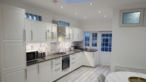 Una cocina moderna con armarios blancos, una estufa a gas y un comedor con mesa de mármol.