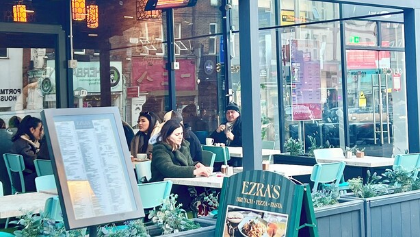 Un restaurante con terraza, un panel con la carta y un cartel de cambio de divisas.