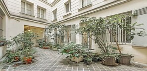 Une cour intérieure agrémentée de plantes en pot et dotée d’un sol carrelé.