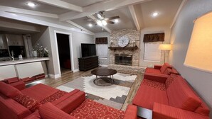 A living room with red sofas, a fireplace, and a kitchen in the background.