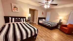 A bedroom with two beds, a ceiling fan, and a red chair.
