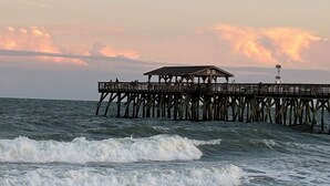 Une jetée qui s’avance dans la mer, avec un petit bâtiment à son extrémité.