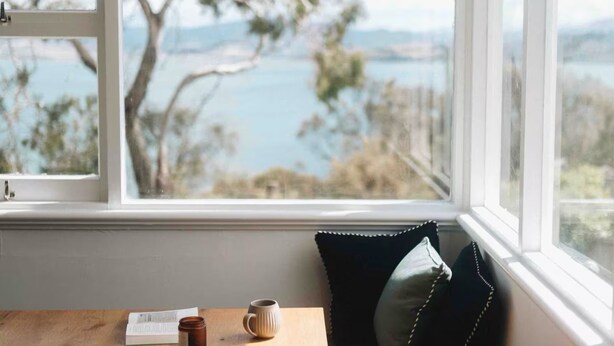 A view from a window with a wooden table, a book, and a mug. - Derwent River Holiday Home - Minutes to Hobart (Midway Point)