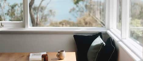 Une vue par la fenêtre, avec une table en bois, un livre et une tasse.