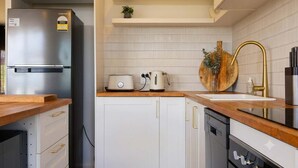 A modern kitchen with a stainless steel refrigerator, white cabinets, a wooden countertop, a sink with a gold faucet, and a toaster. - Derwent River Holiday Home - Minutes to Hobart (Midway Point)