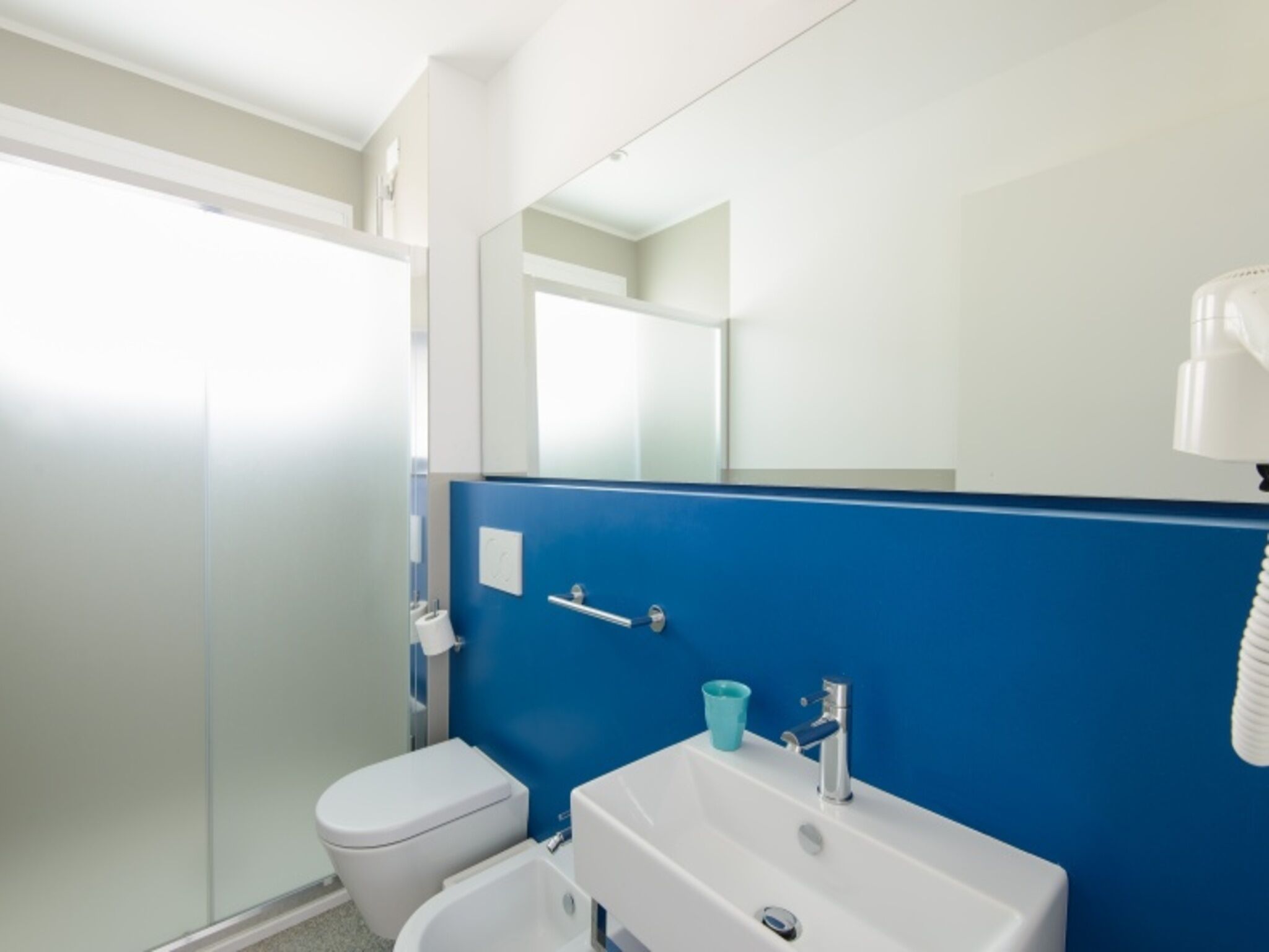 A bathroom with a toilet, a sink, and a mirror.