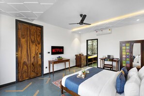 A hotel room with a bed, a desk, a wardrobe, a television, and a mirror.