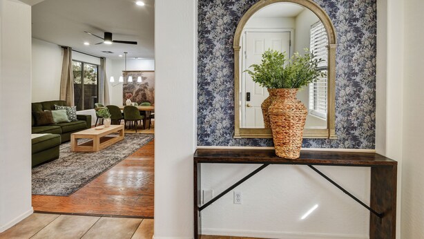 Una sala de estar con sofá, mesa de centro y una planta sobre una consola.