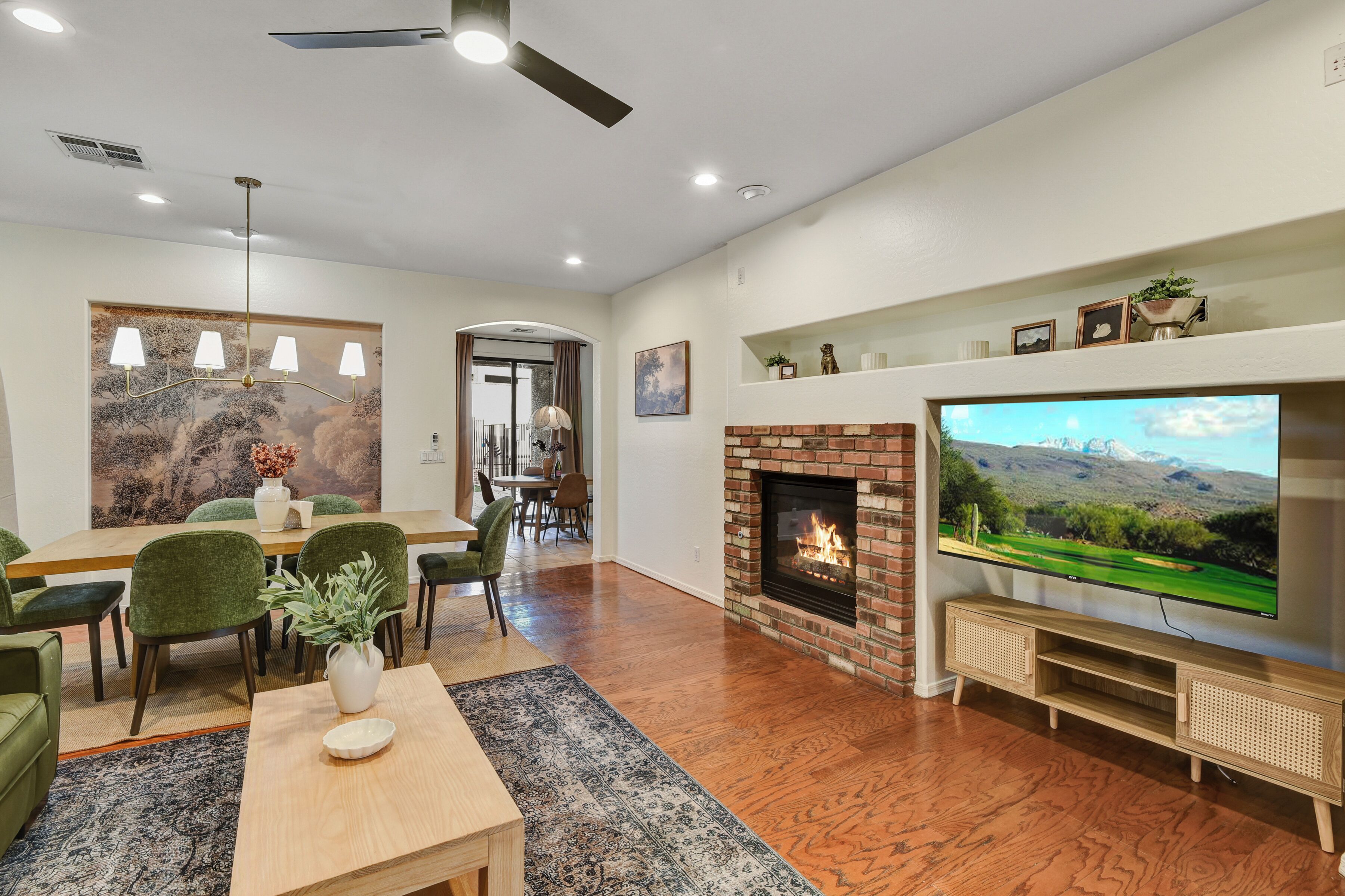A living room with a fireplace, TV, dining area, and a large painting on the wall.