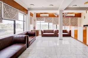 A spacious lobby with leather sofas, large windows, and decorative wall panels.