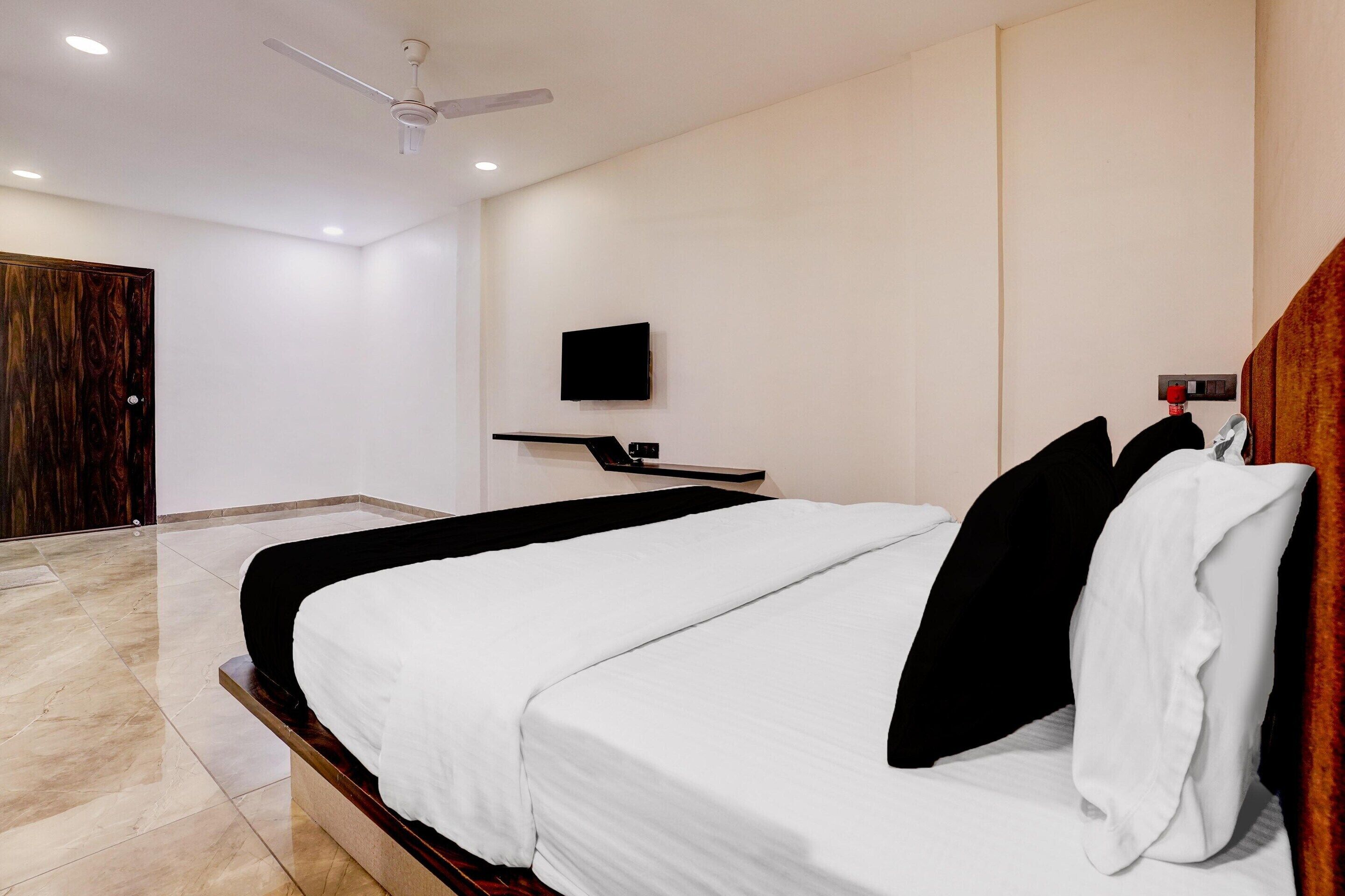 Ein modernes Hotelzimmer mit einem großen Bett, einem flachbildfernseher an der Wand und einem Deckenventilator.