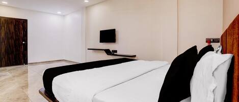 Ein modernes Hotelzimmer mit einem großen Bett, einem flachbildfernseher an der Wand und einem Deckenventilator.