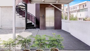 An outdoor area with a lift, potted plants, and a staircase. - Classic The Grand Unity (Garudeshwar)