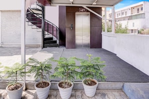 An outdoor area with a lift, potted plants, and a staircase.