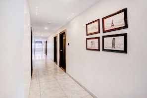 A hallway with framed artwork, doors, and a tiled floor.