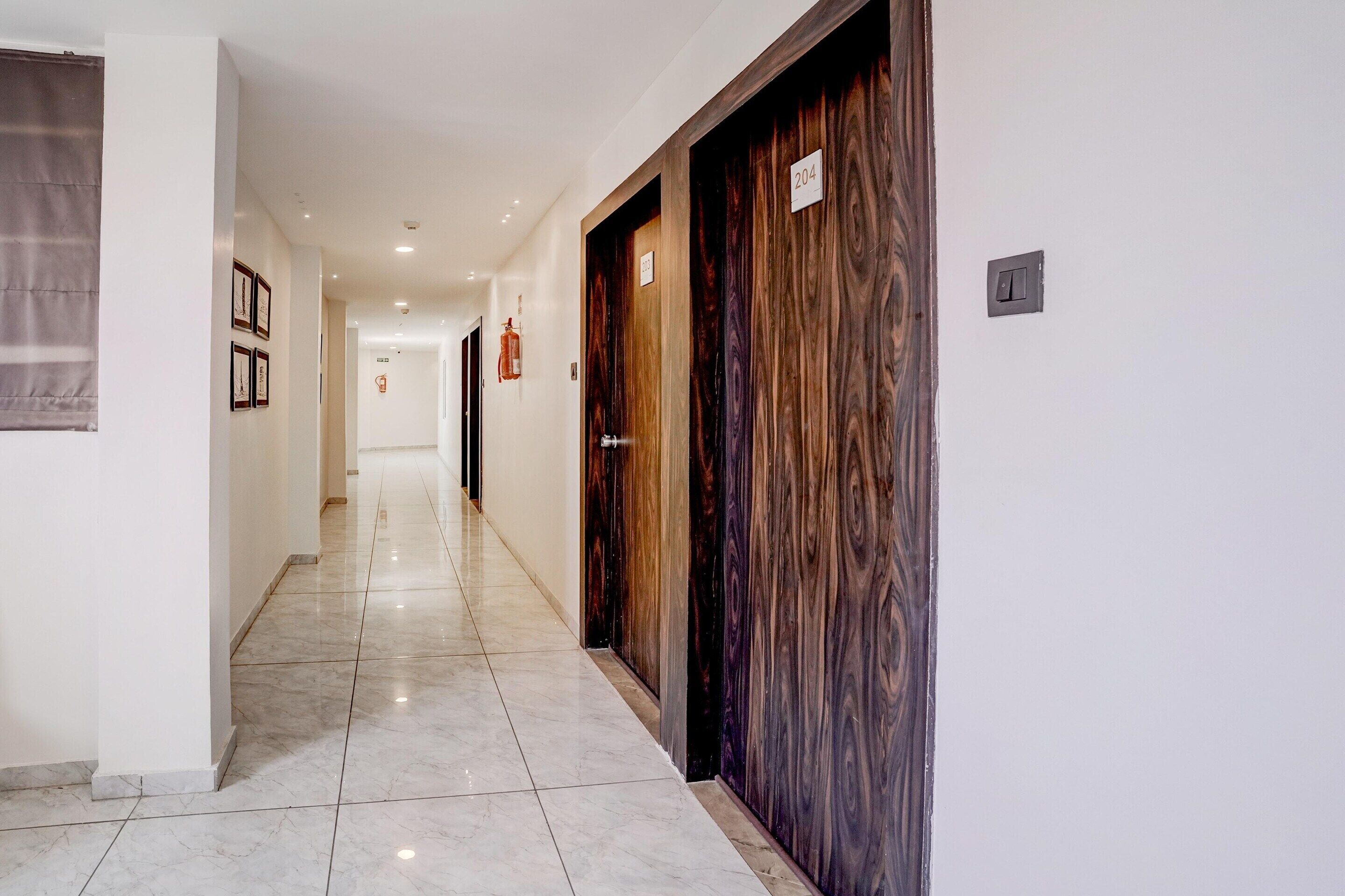 A hotel hallway with a marble floor, wooden doors, and framed pictures on the wall.