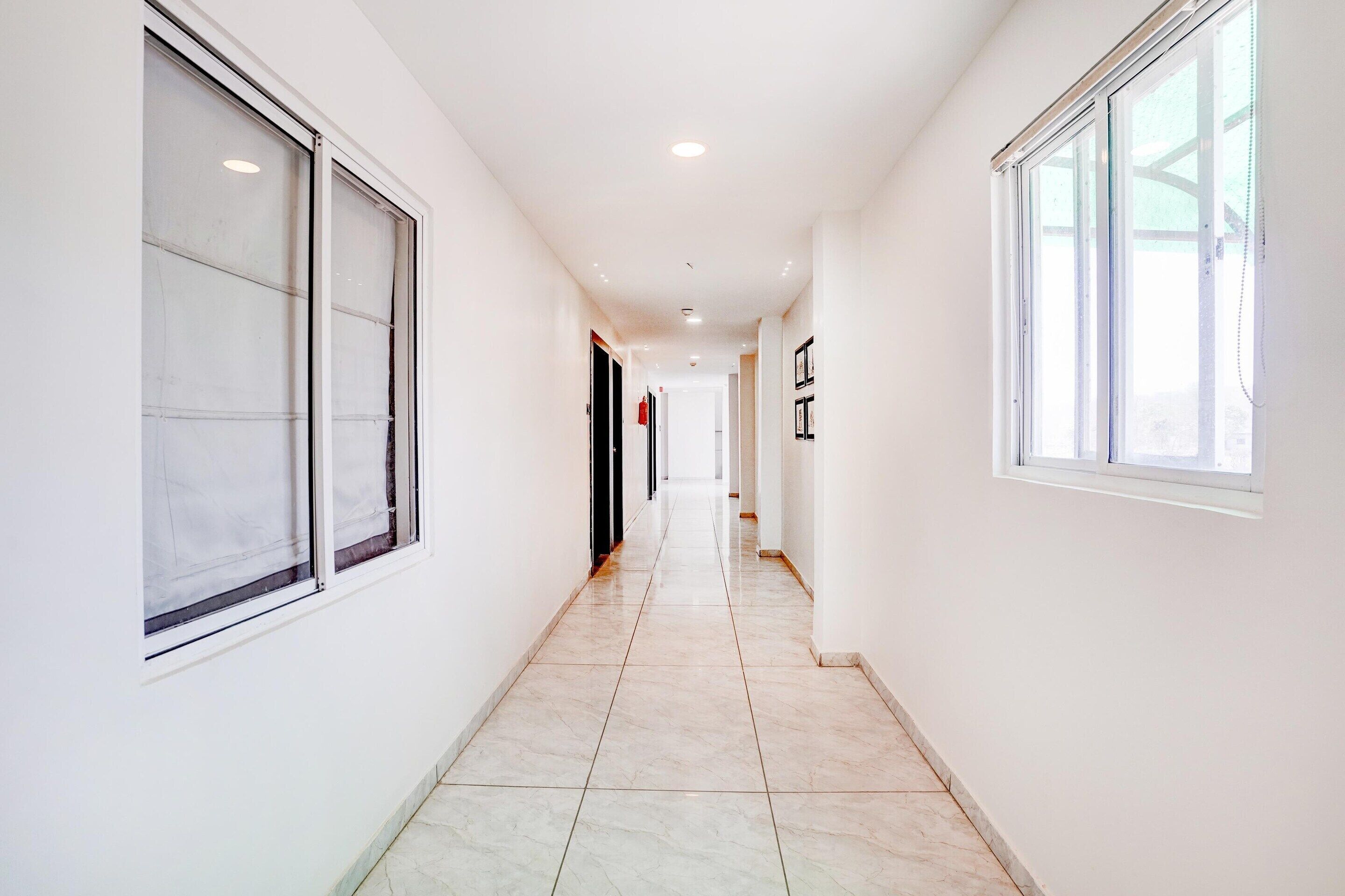 A long, narrow hallway with large windows on both sides, leading to a door at the end.