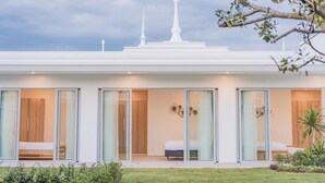 A modern building with large sliding glass doors leading to bedrooms, a flat roof, and a garden area. - The luxury villa Ivory E3 Rawai Phuket (Rawai)