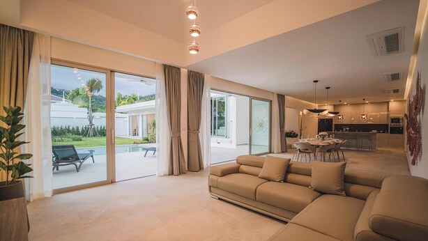 A spacious living area with a large sofa, a dining table, and a kitchen in the background. - The luxury villa Ivory E3 Rawai Phuket (Rawai)