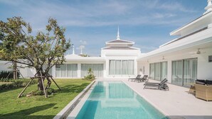 A modern hotel with a swimming pool, a garden, and a traditional-style building in the background. - The luxury villa Ivory E3 Rawai Phuket (Rawai)