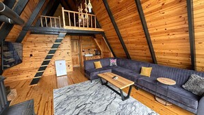 Een loft-achtige kamer met houten inrichting, een bank, een marmeren vloer en een trap.