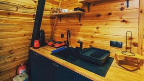 Een houten interieur met een keukenhoek, inclusief een spoelbak, fornuis en planken met glazen.