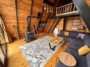 A cozy cabin interior with a wooden interior, a fireplace, a sofa, and a dining table. - Ay Işığı Sapanca Bungalov (Sapanca)