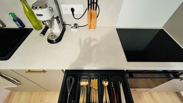 A kitchen with a coffee machine, utensils, and a drawer with various kitchen tools. - Luxury apartment with parking, river and forest views, 5 min. from the center! (La Châtre)