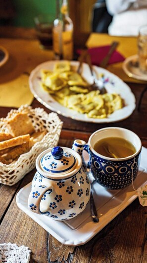 A table with a teapot, a cup of tea, a plate of food, and a basket of bread. - Cozy Cottage Retreat in Berzi (Bajardo)