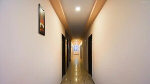 A long, narrow hallway with doors on both sides, a polished floor, and a ceiling light. - Hotel Ganga Inn (Haridwar)