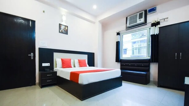 A modern bedroom with a bed, bedside tables, a wardrobe, and a window with curtains. - Hotel Ganga Inn (Haridwar)