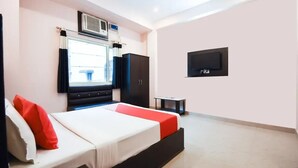 A bedroom with a bed, a TV, a wardrobe, and an air conditioning unit. - Hotel Ganga Inn (Haridwar)