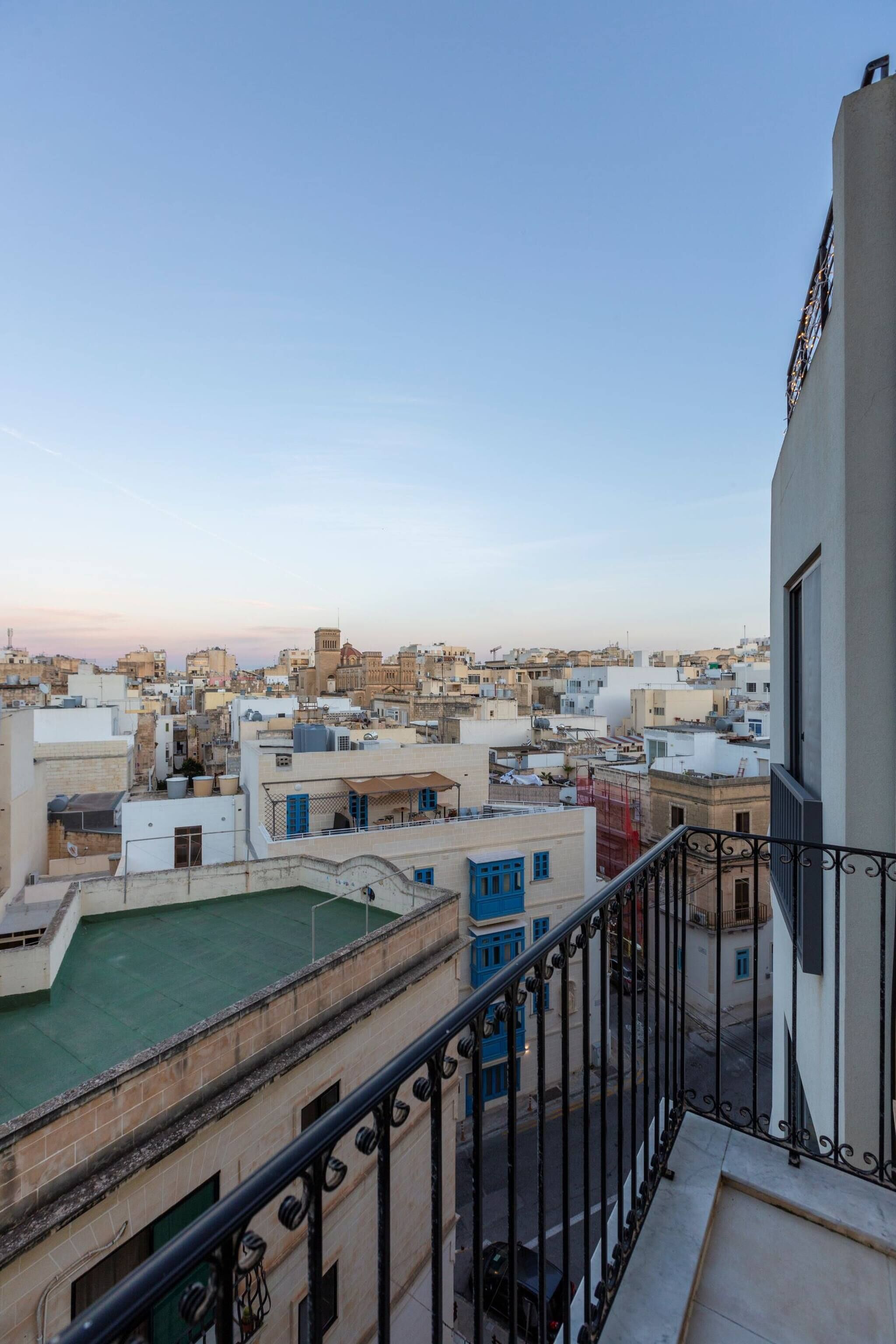 A cityscape with buildings, a balcony, and a clear sky.