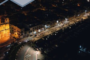 An aerial view of a cityscape at night with illuminated buildings, a prominent church, and a waterfront area with parked boats. - Central Msida 2BR | Near University & College (Msida)