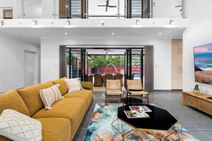 A spacious living area with a sofa, chairs, a coffee table, and a TV.