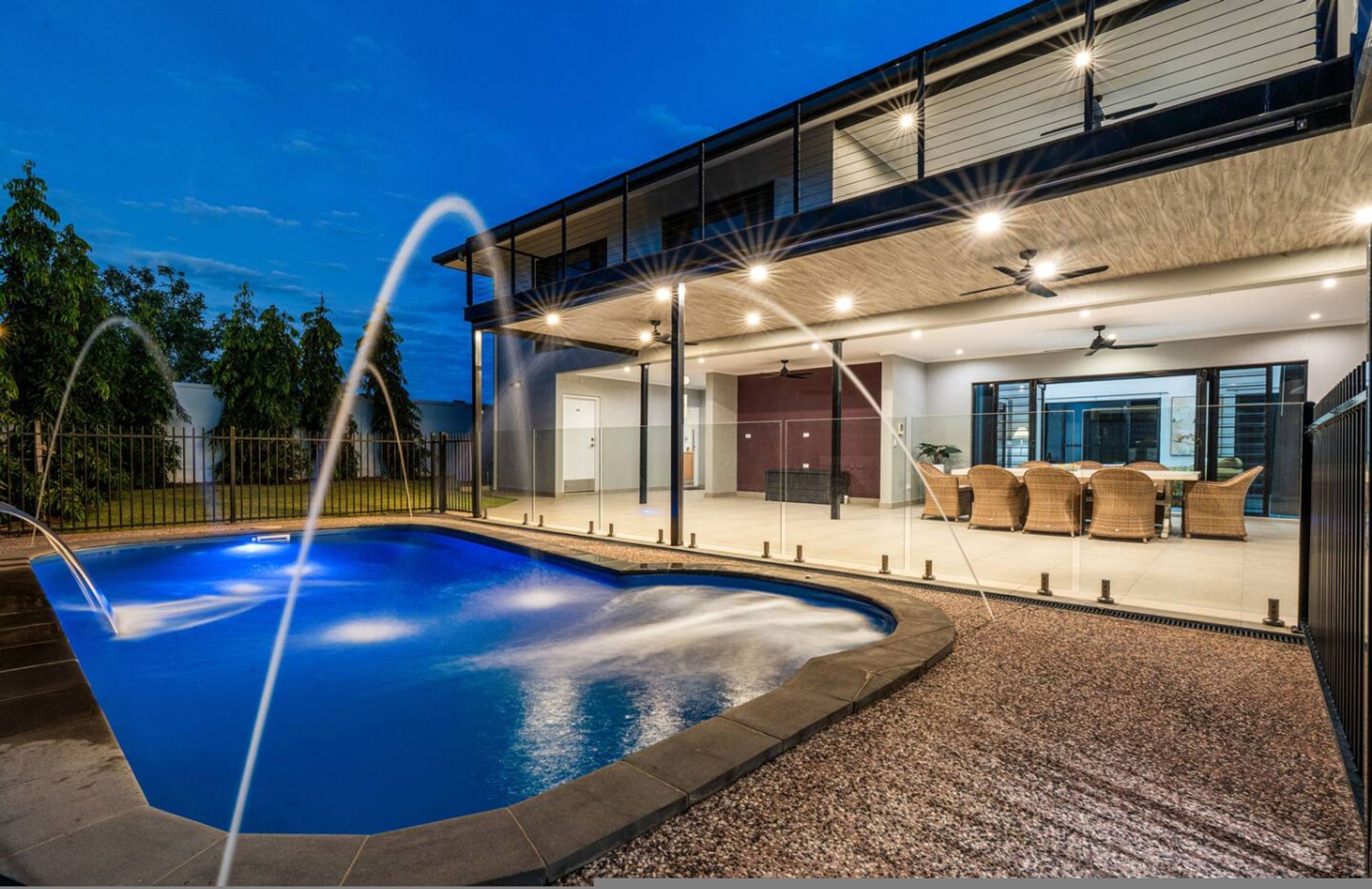 Ein modernes Haus mit Swimmingpool, Sitzgelegenheiten im Freien und einer überdachten Terrasse.