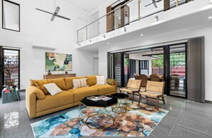 A modern living room with a sofa, chairs, a coffee table, and a large painting on the wall.