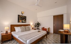A bedroom with a bed, nightstands, a desk, a chair, a plant, a painting, and a ceiling fan. - Casa Toledo 4BR in Candolim w Pvt Pool Near Beach (Candolim)