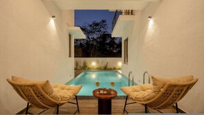 A poolside area with two chairs and a table, a pool, and a view of trees at dusk. - Casa Toledo 4BR in Candolim w Pvt Pool Near Beach (Candolim)