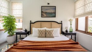 A neatly arranged bedroom with a bed, a potted plant, a painting, and a window with a view. - Casa Toledo 4BR in Candolim w Pvt Pool Near Beach (Candolim)