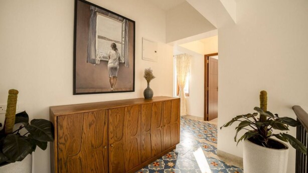 A hallway with a wooden cabinet, a painting, and a potted plant. - Casa Toledo 4BR in Candolim w Pvt Pool Near Beach (Candolim)
