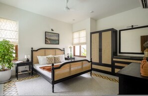 Un dormitorio con cama, mesita de noche, lámpara, planta en maceta y un espejo grande.