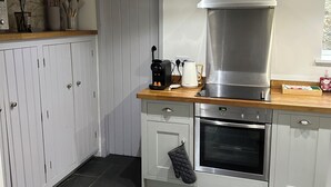 A kitchen with a stove, oven, and a large range hood. There are cabinets, a countertop, and a door. - 2, THE LODGE, TIDESWELL (Tideswell)