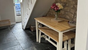 A staircase with white railings leading to an upper level, a wooden table with a vase of flowers, and a stone wall. - 2, THE LODGE, TIDESWELL (Tideswell)