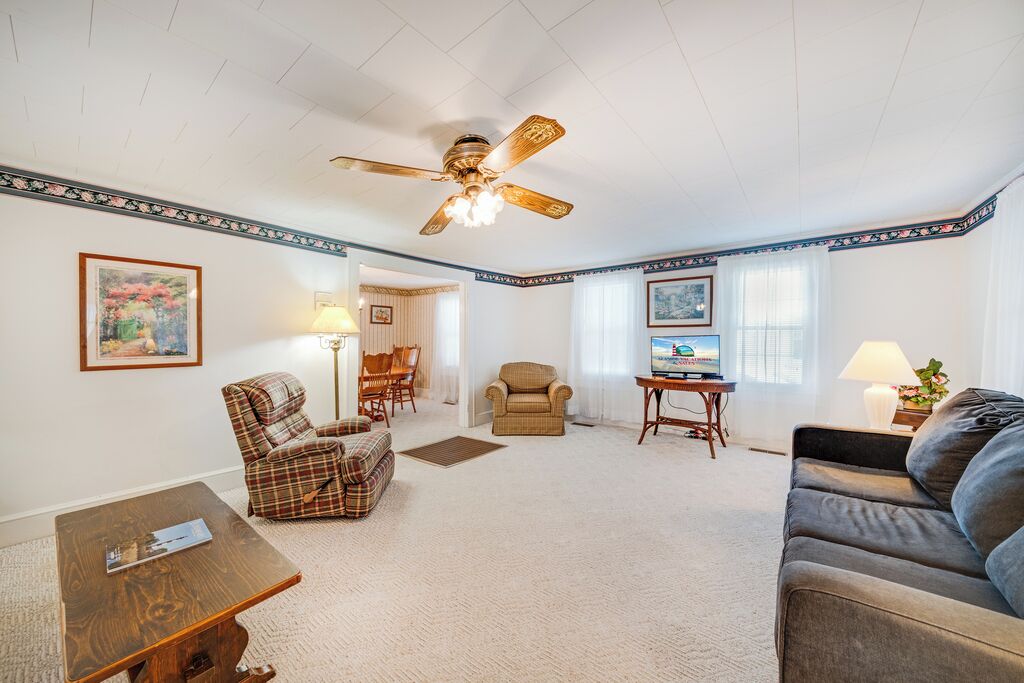 A living room with a ceiling fan, a television, a sofa, a chair, and a coffee table.