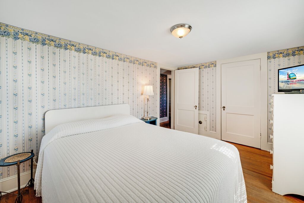 Une chambre d’hôtel équipée d’un lit, d’un bureau, d’une lampe, d’une télévision et d’une armoire.