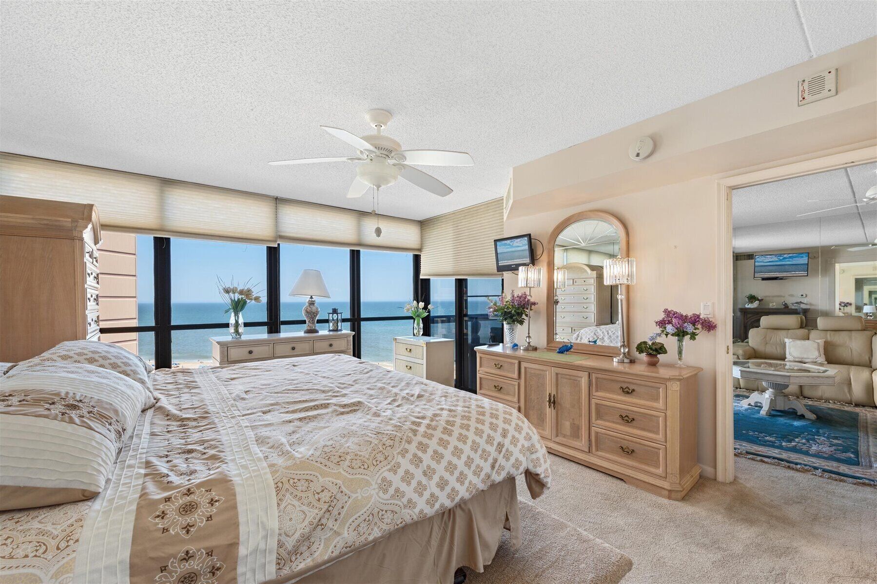 Un dormitorio con cama, cómoda y ventanas amplias con vistas al océano.