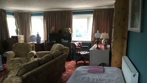 A room with a bed, a wooden chair, a sofa, a desk with a lamp, and a dresser. - Wansley Manor (Birmingham)