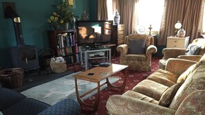 A living room with a sofa, armchairs, a television, a bookshelf, and a fireplace. - Wansley Manor (Birmingham)